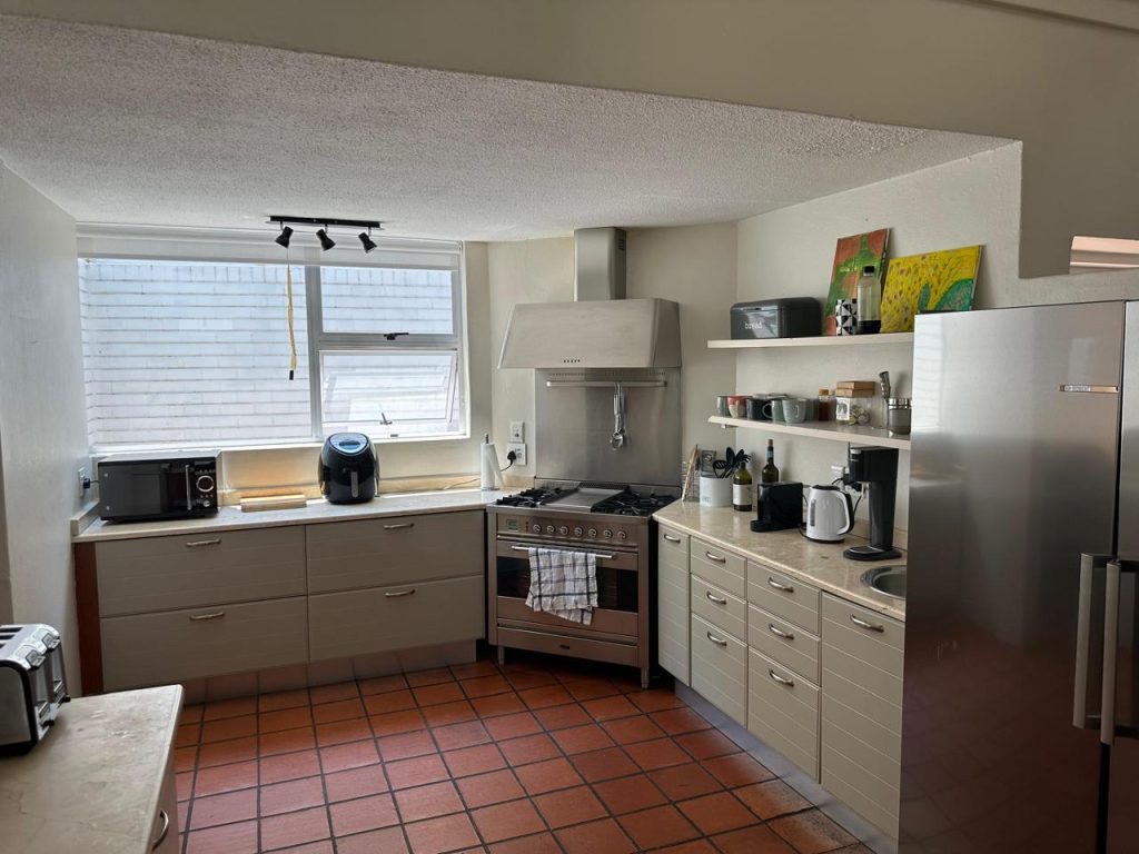Kitchen with terracotta flooring and dated cabinetry before renovation, Benmore Gardens