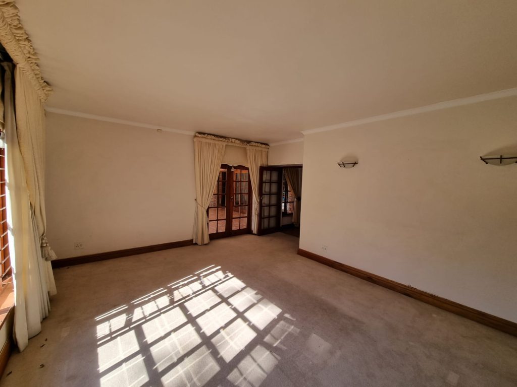 Original room with carpeted floor and dated curtaining lit by side windows.