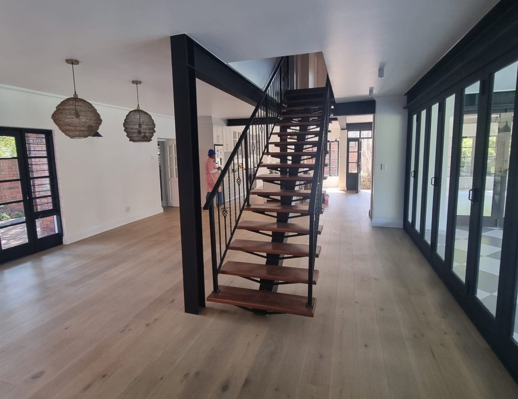 Renovated open living area with a black steel and timber staircase and full-height garden glazing.