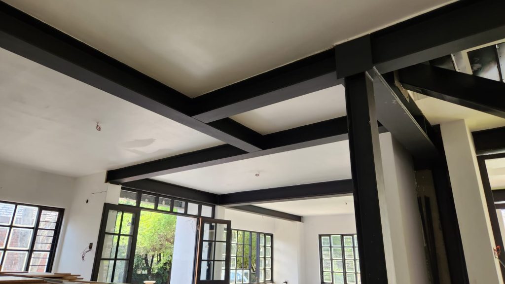 Close view of the exposed steel I-beam ceiling structure framing the new open-plan level.