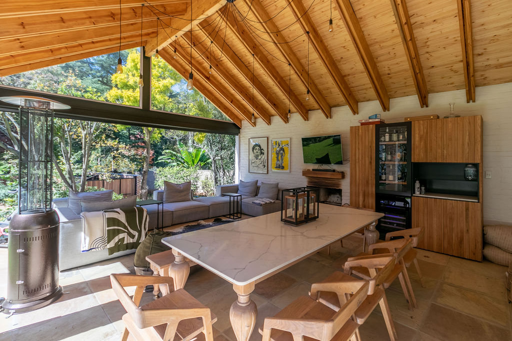 Covered patio living area with marble-topped dining table, built-in cabinetry, and fireplace.